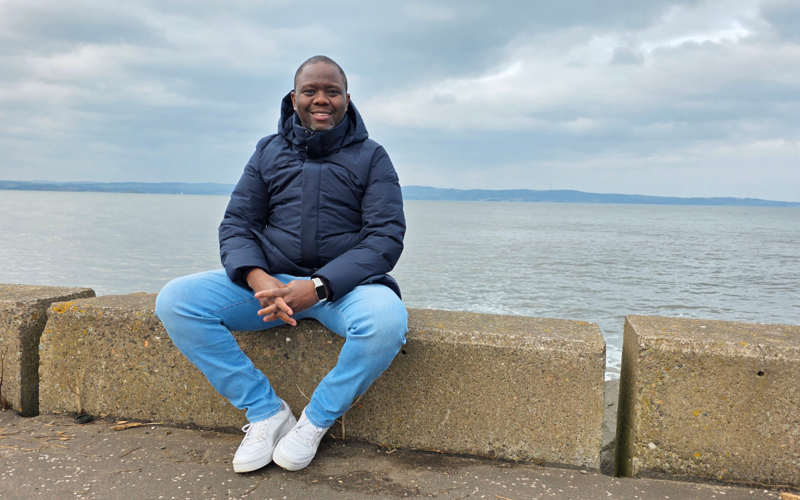 Linus Chirchir sits on a wall at the shore