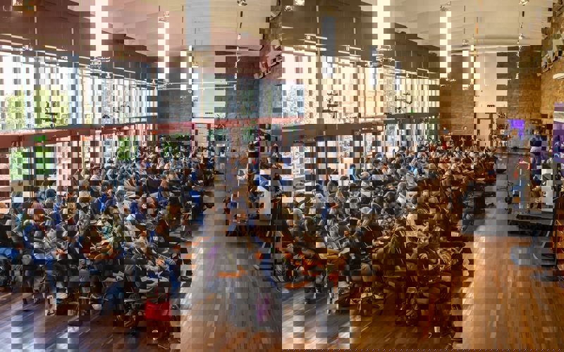 A group of people sitting in chairs in a room with a person speaking