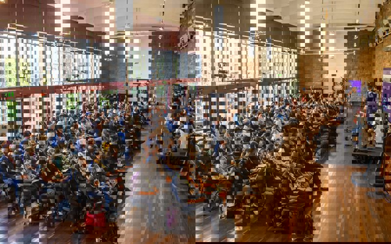 A group of people sitting in chairs in a room with a person speaking