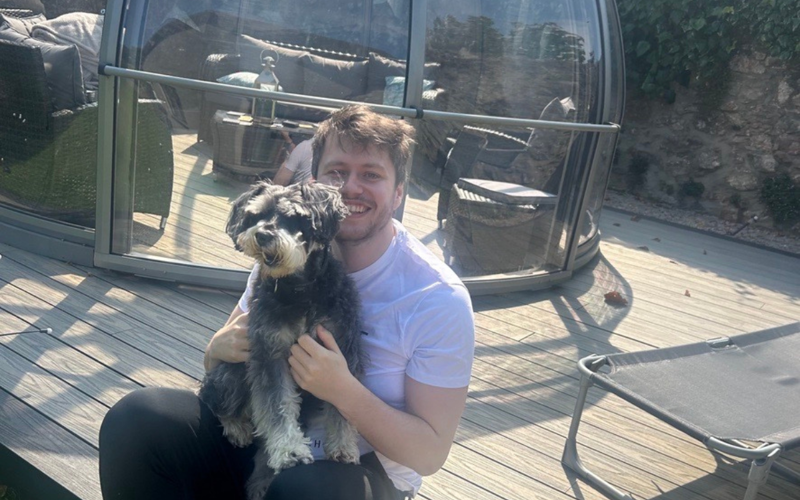 Ryan Bremner, man sitting on wooden decking with grey dog.