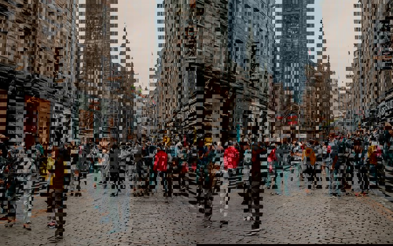 A crowd of people stand on a cobbled Edinburgh street