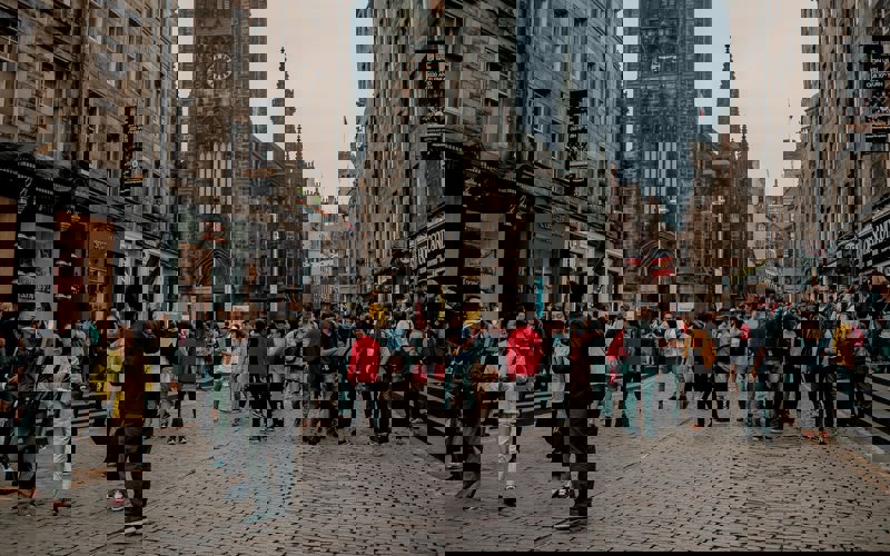 A crowd of people stand on a cobbled Edinburgh street