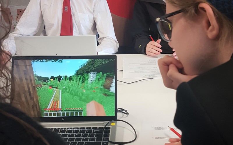 A schoolchild looking at a laptop with Minecraft on the screen