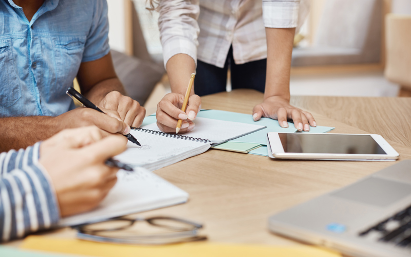 people working at a table strewn with paper and devices